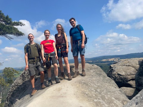 Das Team steht auf einem Felsplateau mit Aussicht auf die Landschaft