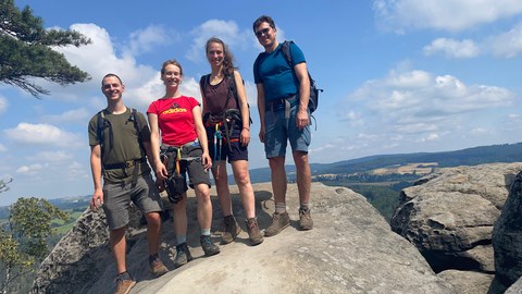 Das Team steht auf einem Felsplateau mit Aussicht auf die Landschaft