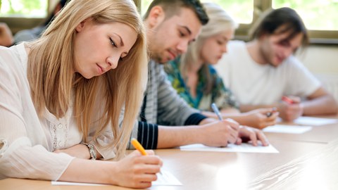 Das Foto zeigt Studierende, die konzentriert eine Klausur schreiben.