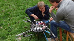 Two men sitting and watching a drone