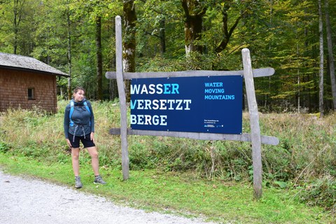 Franzi vor Schild mit "Wasser versetzt Berge"-Aufschrift