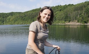 Smiling person in front of a standing water