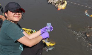 Kenyum hockt in einem verunreinigten Fluss in Indien, während sie Wasserproben nimmt