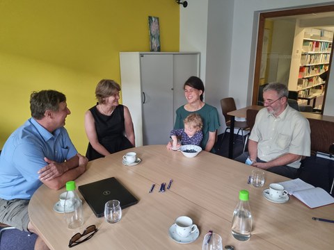 eine Gruppe aus 4 Personen (2 Männer, 2 Frauen) sitzt an einem Runden Tisch mit diskutiert