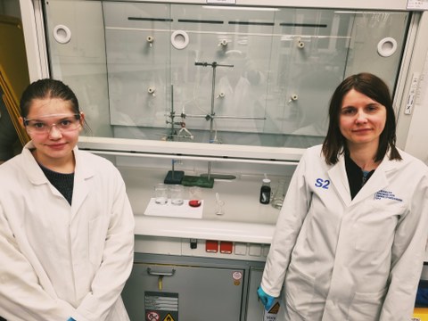 Das Bild zeigt zwei Personen in Arbeitschutzkittel in einem Labor.