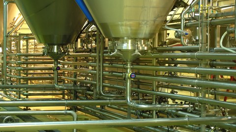 Fabrikhalle mit Behälter und Rohrleitungen aus Edelstahl