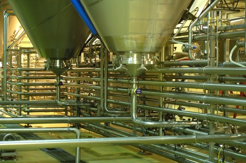 Fabrikhalle mit Behälter und Rohrleitungen aus Edelstahl