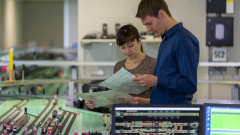 Betreuerin und Student stehen im Labor und schauen auf Unterlagen.