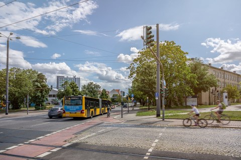 Foto des Verkehrs auf dem TU-Gelände mit Fahrradfahrern, Autos und dem Bus "61".