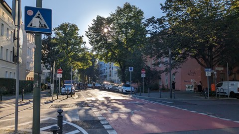 Das Foto zeigt eine Straßenkreuzung im Komponistenviertel. Zu sehen sind rote Fahrbahnmarkierungen im Kreuzungsbereich mit Fahrradpiktogramm. 