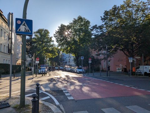 Das Foto zeigt eine Straßenkreuzung im Komponistenviertel. Zu sehen sind rote Fahrbahnmarkierungen im Kreuzungsbereich mit Fahrradpiktogramm. 