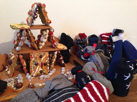 Das Bild zeigt ein Pfefferkuchenhaus sowie Socken, die als Adventskalender genutzt werden. 