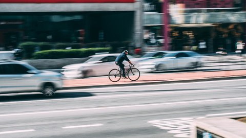 Ein Radfahrer auf einer stark befahrenen großen Straße.