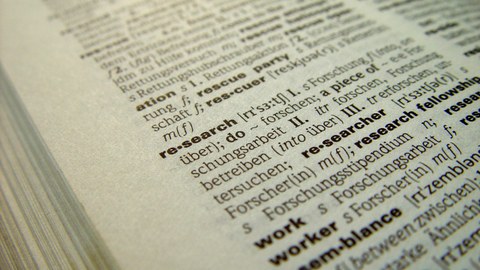 Das Foto zeigt die Seite eines aufgeschlagenen Wörterbuchs. Im Zentrum des Bildes steht das Wort "research".