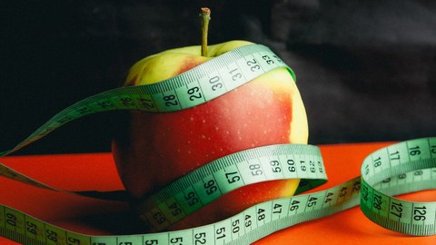 Das Foto zeigt einen Apfel, der von einem Maßband eingekreist ist.
