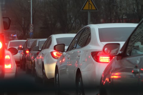Auto-Stau: mehrere Autos stehen hiontereinander dicht an dicht. Ihre Rücklichter und teilweise Bremslichter sind an.