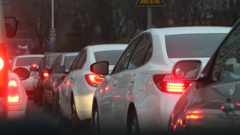 Auto-Stau: mehrere Autos stehen hiontereinander dicht an dicht. Ihre Rücklichter und teilweise Bremslichter sind an.