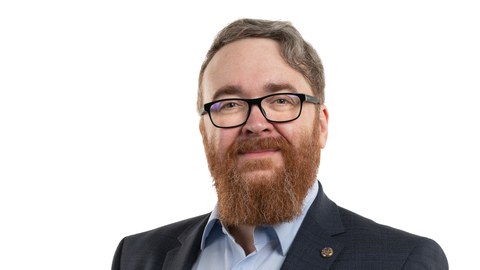 Porträt eines Mannes mit grau-rotem Haar und Vollbart sowie Brille