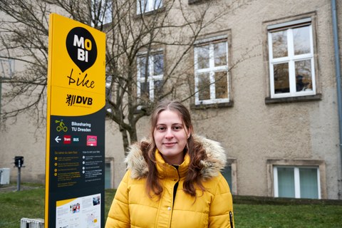 Eine junge Frau in gelber Jacke steht vor einem MobiPunkt in Dresden