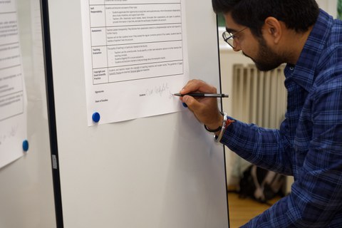 Das Bild zeigt einen Studierenden beim Unterzeichnen des Lehr-Lern-Agreements