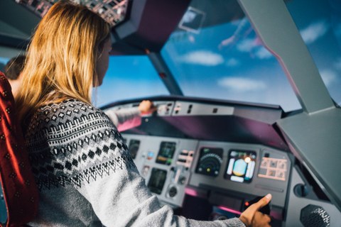 Eine Studentin sitzt im Flugsimulator und schaut aus den Fenstern im Cockpit.