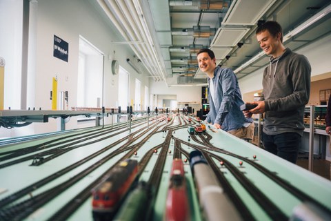 Zwei Studierende blicken über das Miniatur-Eisenbahnfeld des Eisenbahnbetriebslabors.
