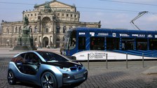 E-Auto und Straßenbahn mit Branding der technischen Universität Dresden vor der Semperoper