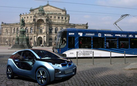 E-Auto und Straßenbahn mit Branding der technischen Universität Dresden vor der Semperoper