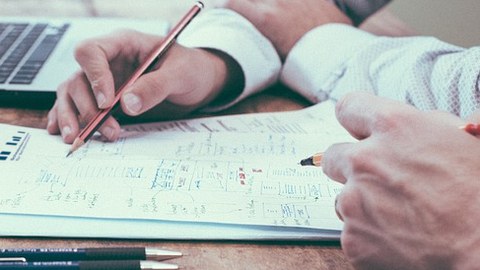 Zwei Herren besprechen Notizen mit Blei- und Rotstift
