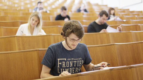 Ein Student sitzt im Hörsaal während einer Prüfung