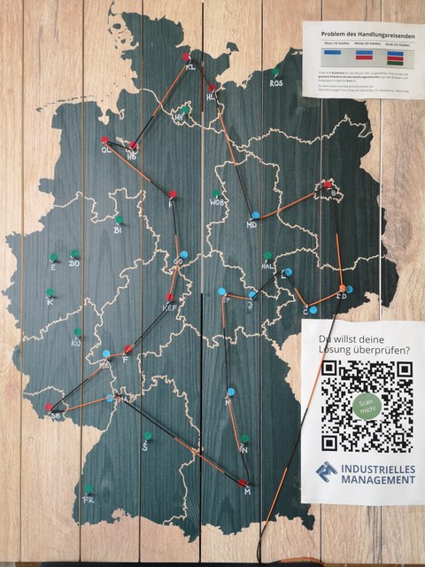 Deutschlandkarte auf Holz, auf der mit einem Faden eine möglichst kurze Tour durch alle größeren Städte gefunden werden soll.