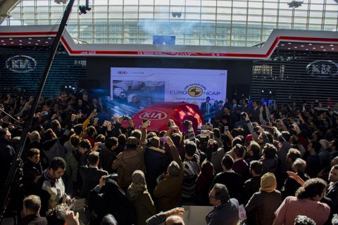 Crowd in front of a car in an exhibition hall. 