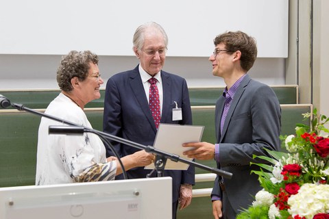 Das Bild zeigt 2 Männer und eine Frau bei einer Urkundenübergabe.