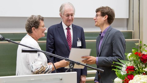The picture shows two men and one woman handing over a certificate.