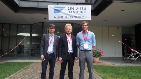 3 men in suits in front of a building. 