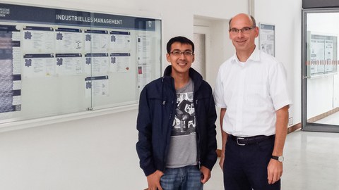 2 men in front of an information board.