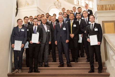 Gruppenbild auf einer Treppe. Manche Personen halten Urkunden in der Hand.