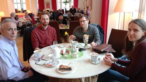 4 people are sitting at a round table in a café.