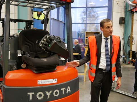 Ein Mann zeigt auf einen Gabelstapler der Marke "Toyota".