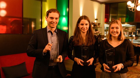 1 man and 2 women with glass cups in their hands.