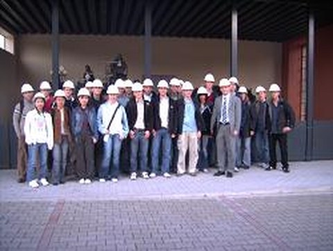 Excursion team at the factory site wearing safety helmets.