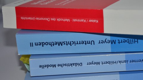 Foto von vier Büchern der Wirtschaftspädagogik, die übereinander gestapelt auf einem Tisch liegen.