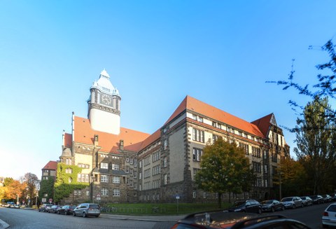 Das Foto zeigt die Außenansicht des Georg-Schumann-Baus der TU Dresden. Charakteristisch ist der Wehrturm und das burgähnliche Aussehen des Gebäudes.