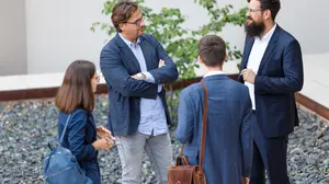 You can see a group of people, three men and one woman talking to each other 