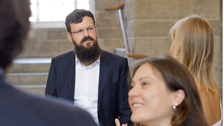 Professor and several students. They are standing in the foyer of the Schumann Building of the TU Dresden and talking.
