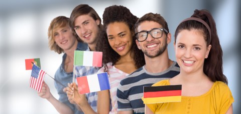 Auf dem Bild sind 5 Studierende, unterschiedlicher Nationalität zu sehen. Diese halten jeweils eine kleine, eigene Länderflagge.