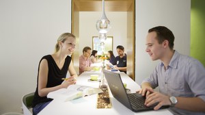 Zu sehen sind eine Studentin und ein Student, die in der coffeebar "Ins Grüne" sitzen und arbeiten