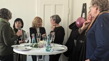 Es ist eine Gruppe von Menschen zu sehen, die sich bei einer Feier unterhalten