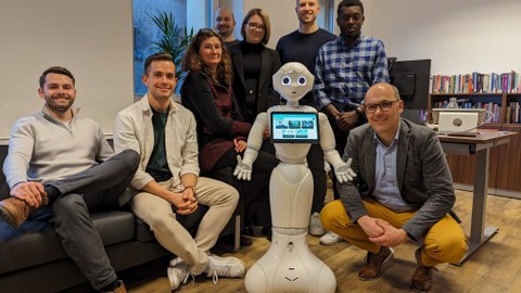 Zu sehen ist das Team der Professur fürn Finanzwirtschaft mit einem Roboter  
