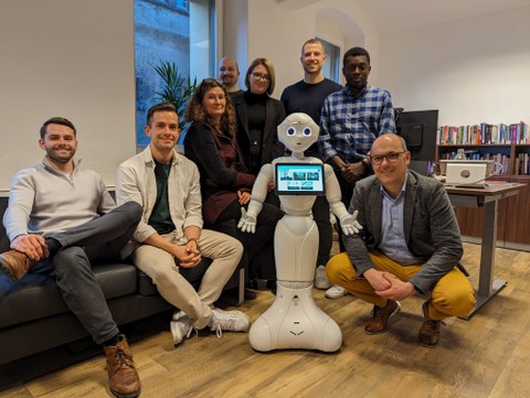 Zu sehen ist das Team der Professur fürn Finanzwirtschaft mit einem Roboter  